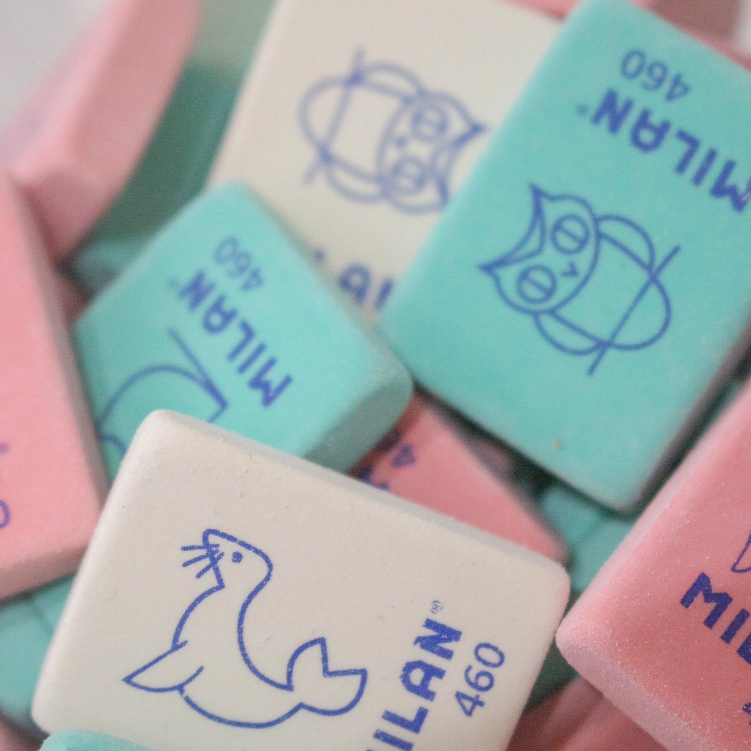 Close-up of several mini rectangular Milan erasers in pink, white and green, each with a different animal illustration on.