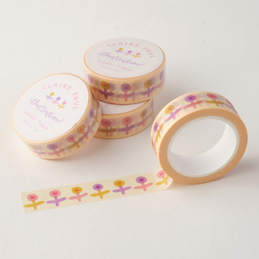 Stack of Pastel Buds washi tapes in their packaging with an open roll. Tapes feature a lilac, pink and yellow flowers on a cream background. Each roll measures 15mm wide and has 10m of tape. Made by Claire Paul. 