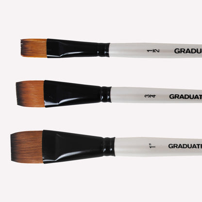 Daler Rowney Graduate flat wash paintbrushes with synthetic filaments, a short white handle and black ferrule, available in sizes 1/2", 3/4" and 1". 