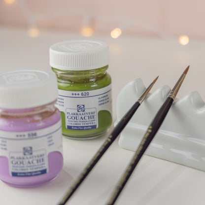 Close up of contents of the Salt Art Supply Gouache Duo and Brush Rest Gift Set with two paints, two artist paintbrushes and a ceramic brush rest. 