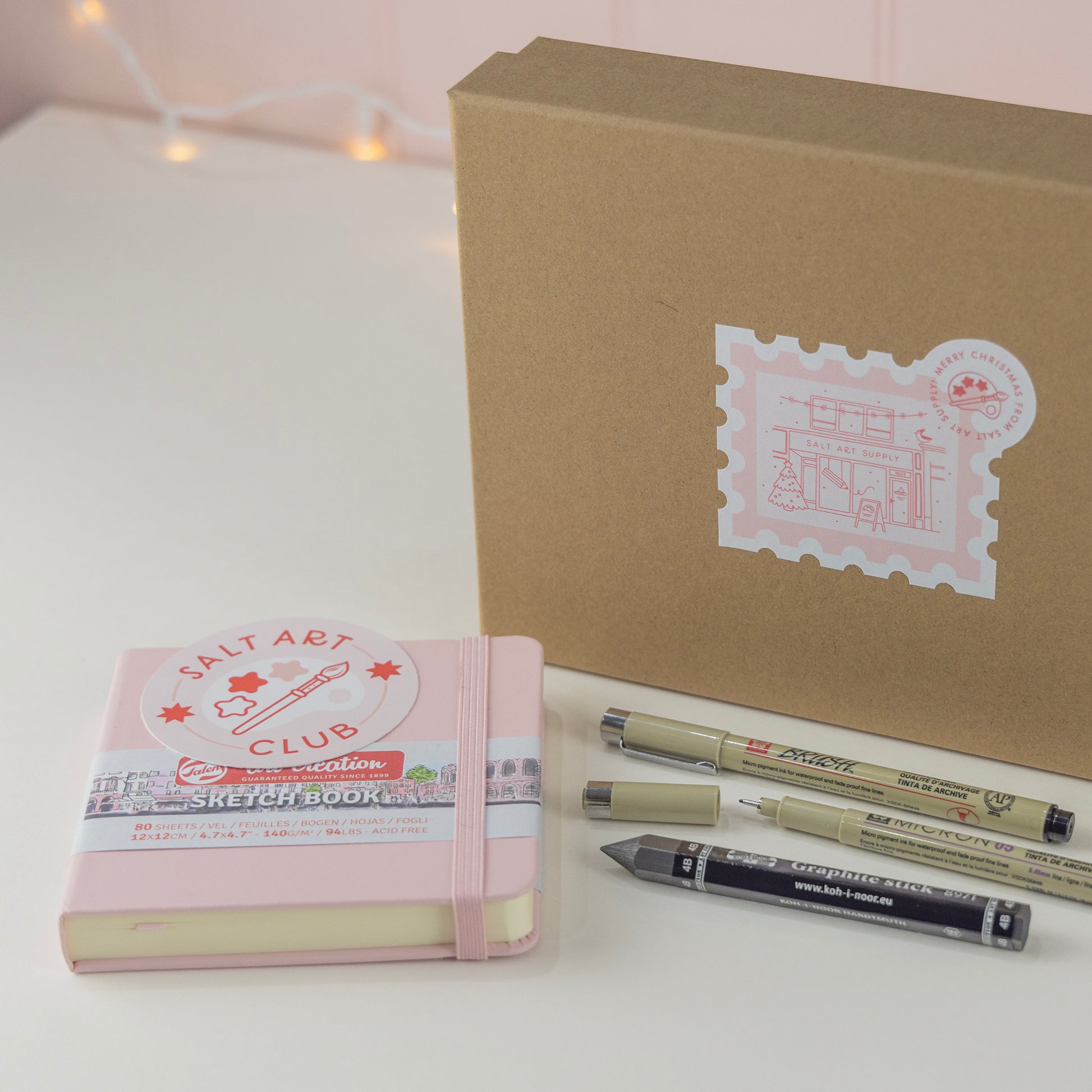 Salt Art Supply "Start a Sketchbook" creative Christmas Gift Box including a pink sketchbook, three drawing tools and a Salt Art Club sticker. 