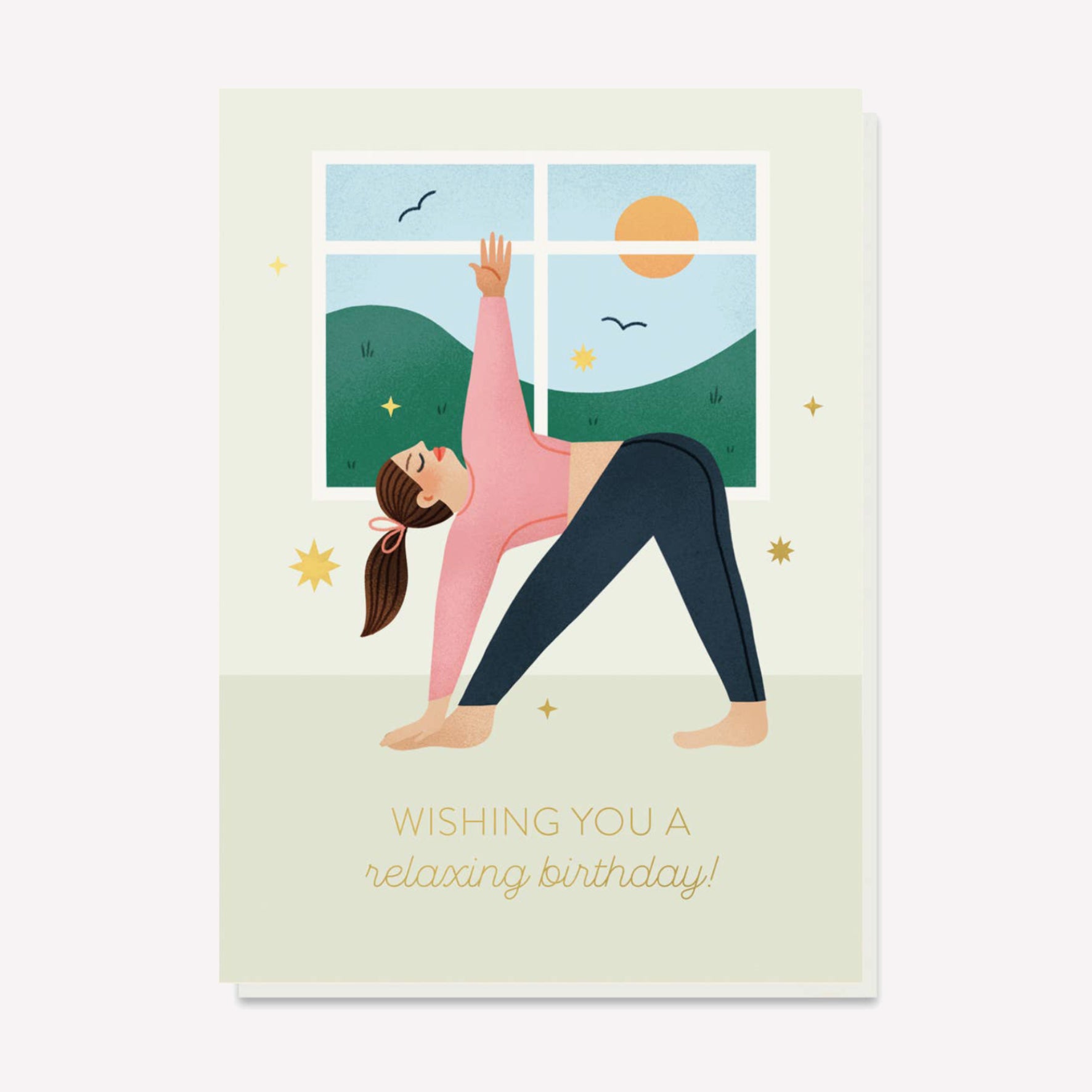 A relaxing gold foil birthday card featuring a sunny yoga studio illustration and warrior pose. Text reads "Wishing you a relaxing birthday". 