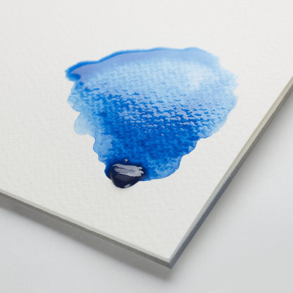 Swatch of Winsor & Newton's coldpressed watercolour paper with blue paint sitting on the medium grained surface. Suitable for a range of painting techniques. 